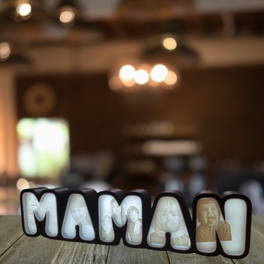 Lettrage décoratif "MAMAN" avec des photos intégrées, sur une table en bois.